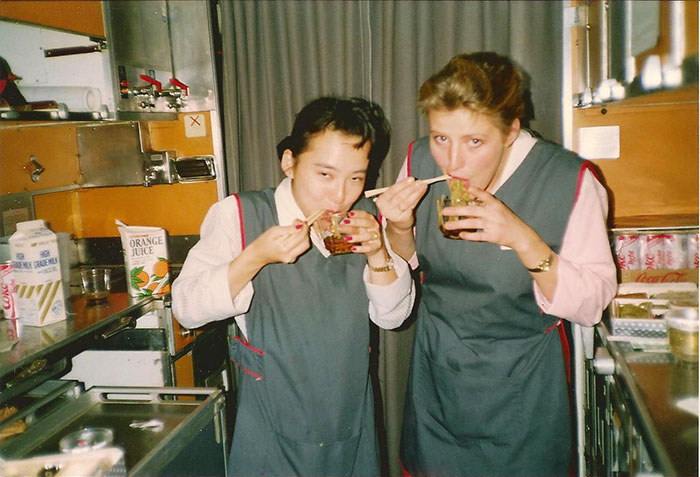 A Japanese and British Virgin Atlantic stewardess eating noodles in the galley